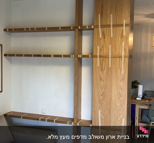 מדפי עץ מותקנים על קיר עם סרטי הדבקה